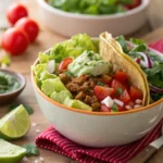A taco bowl filled with fresh vegetables, guacamole, and seasoned meat
