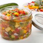 Homemade pickle salsa in a bowl made with diced pickles, tomatoes, onions, cilantro, and jalapeños, offering a tangy and savory flavor perfect as a dip or sandwich topping.